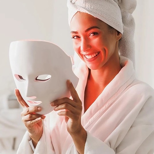 Woman holding a Glokore LED skincare mask during an at-home beauty routine